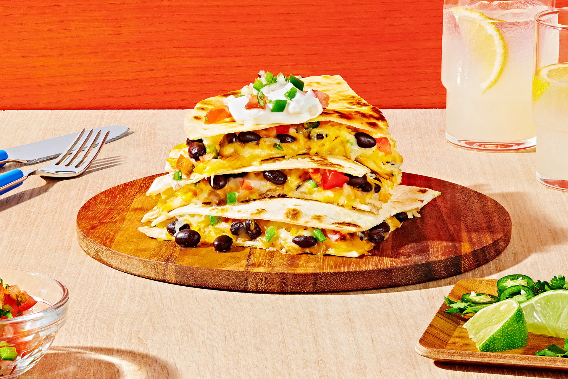 Three pieces of black bean quesadillas stacked on top of each other on a wooden plate