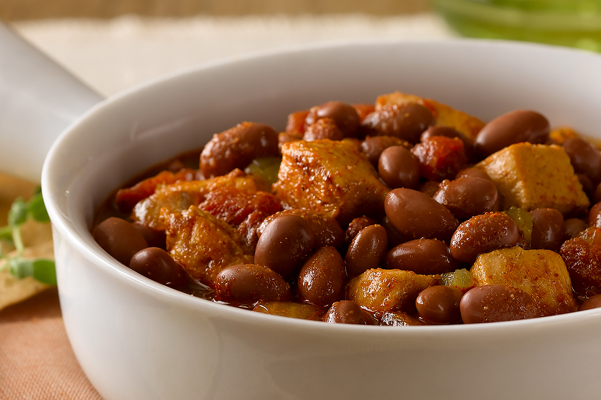 Spicy stovetop chicken and beans with tomatos in a white bowl