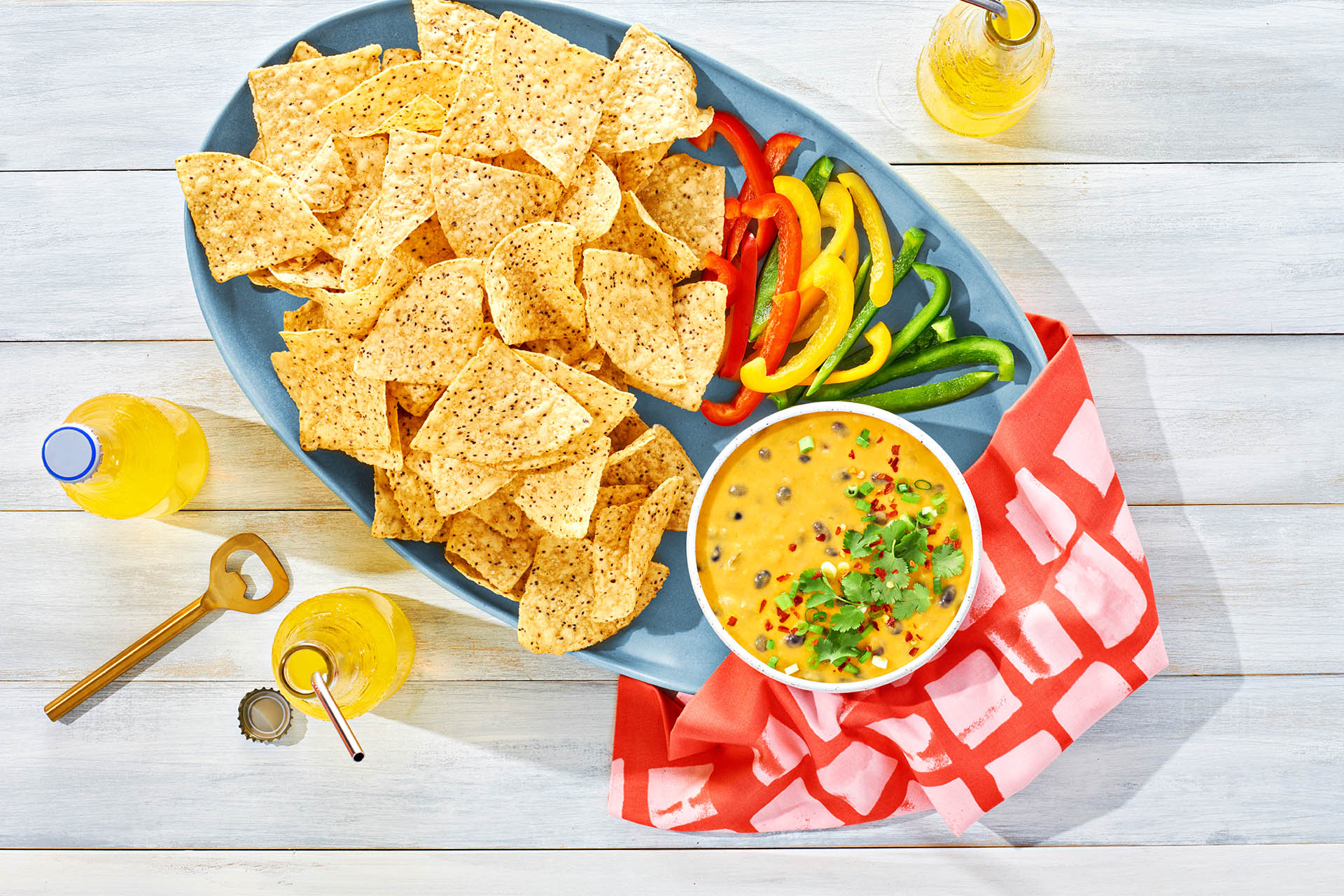 Dish of Black Bean Con Queso Dip with corn chips and pepper slices.
