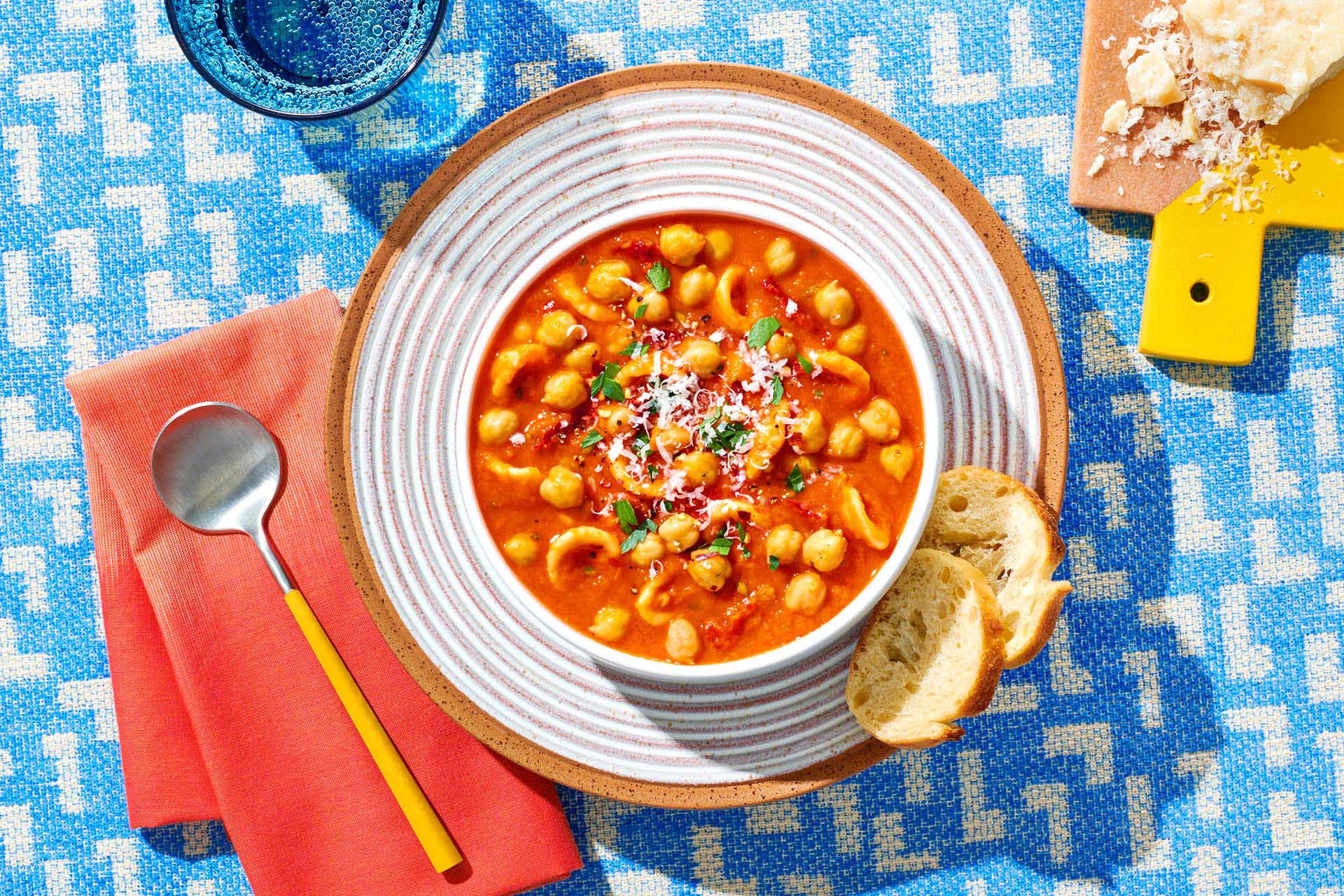 A bowl of Tuscan garbanzo bean and sun dried tomato soup with toast rounds on a plate