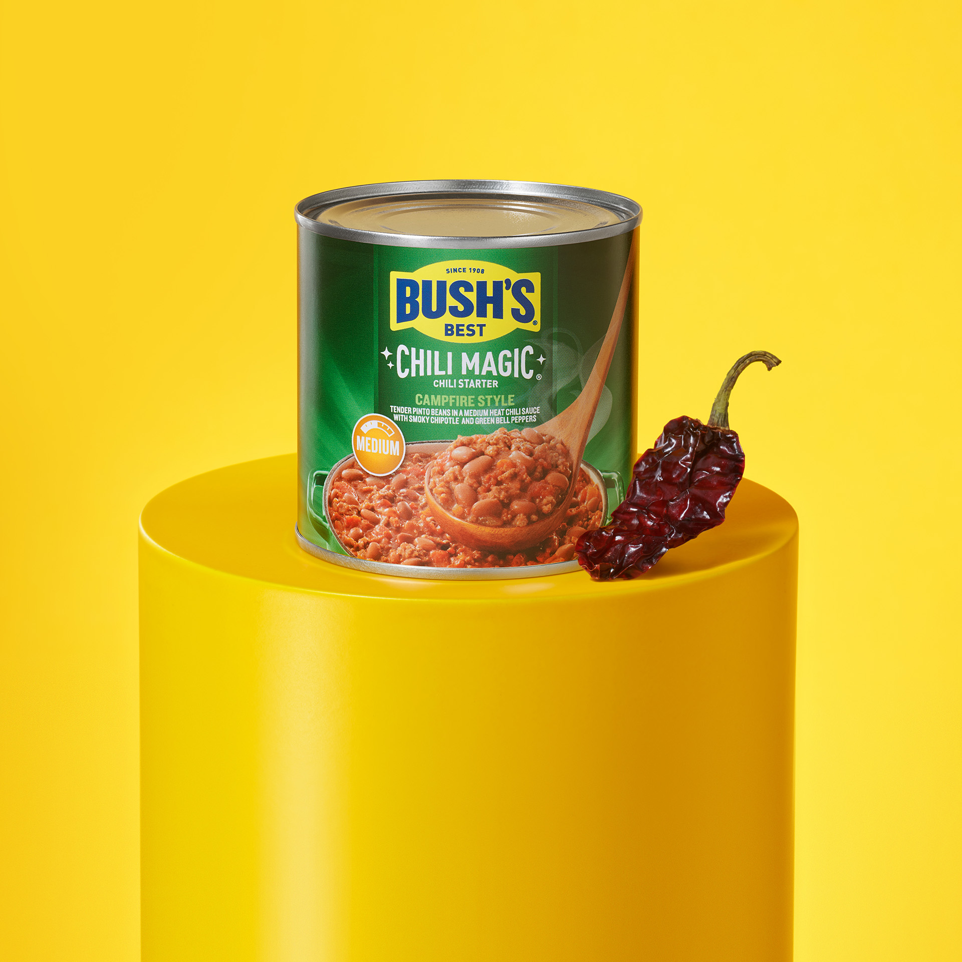 Can of Bush’s Chili Magic Campfire Style on a pedestal with a dried pepper.