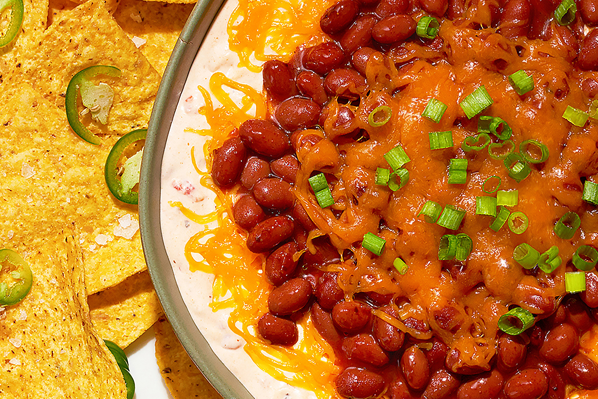 Bean and chili cream cheese dip with tortilla chips and jalapenos 