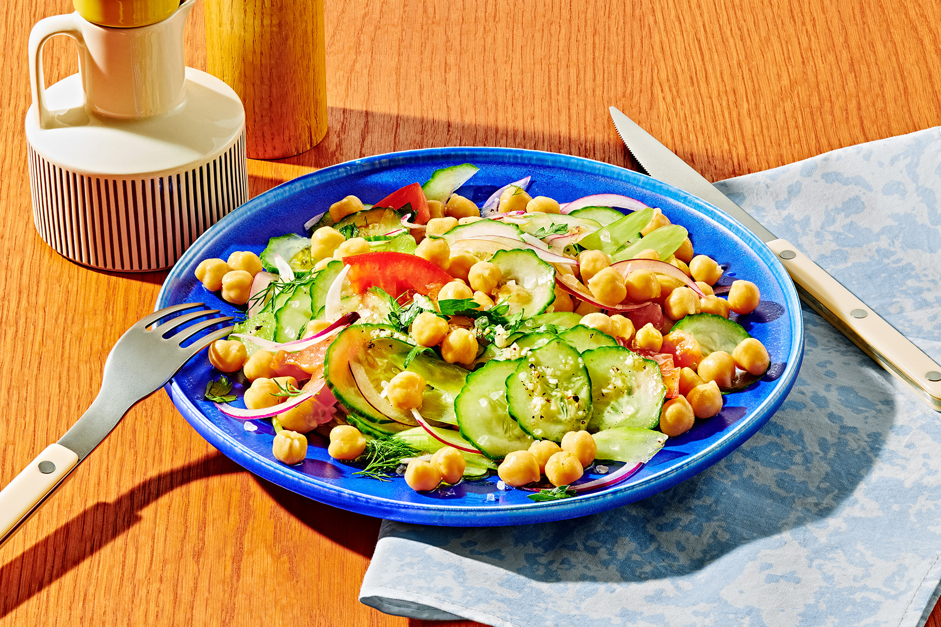 Salad with pickles, garbanzo beans, red onion and herbs in a blue bowl