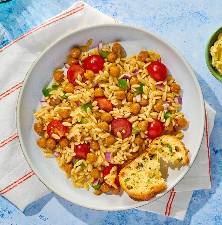 Chickpea or garbanzo beans orzo pasta salad with tomatoes, peppers, and onion.