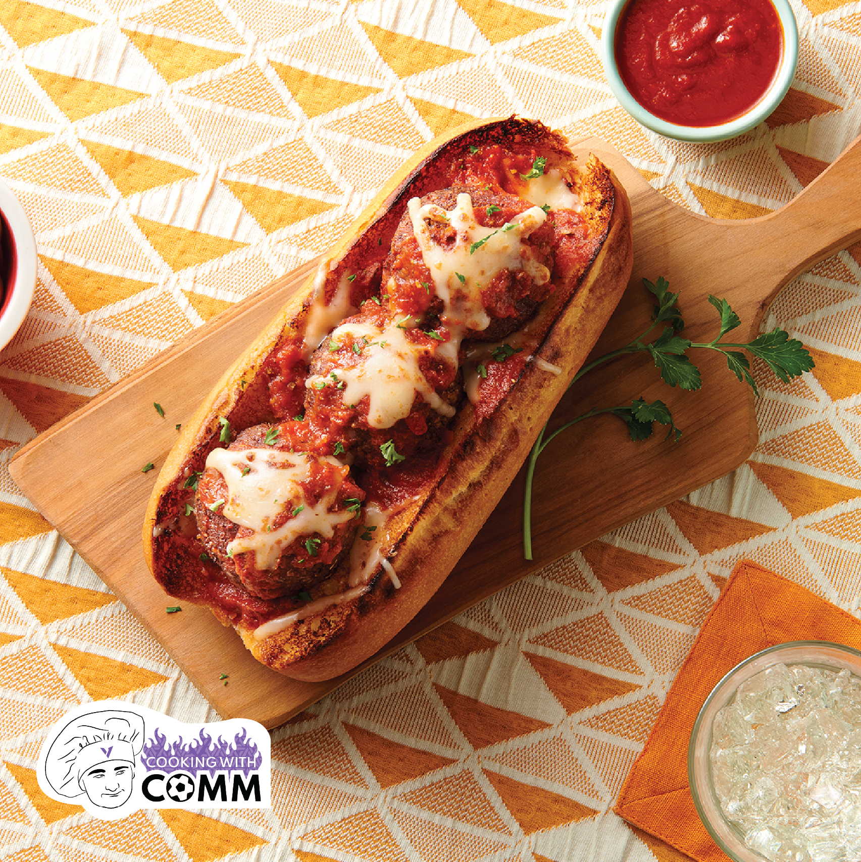 a meatball sub served on a wooden paddle with a cup of sauce next to it.