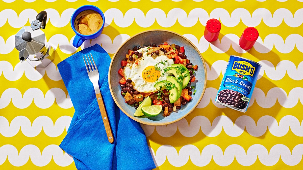 Sweet potato breakfast bowl with black beans, topped with a fried egg and avocado slices.