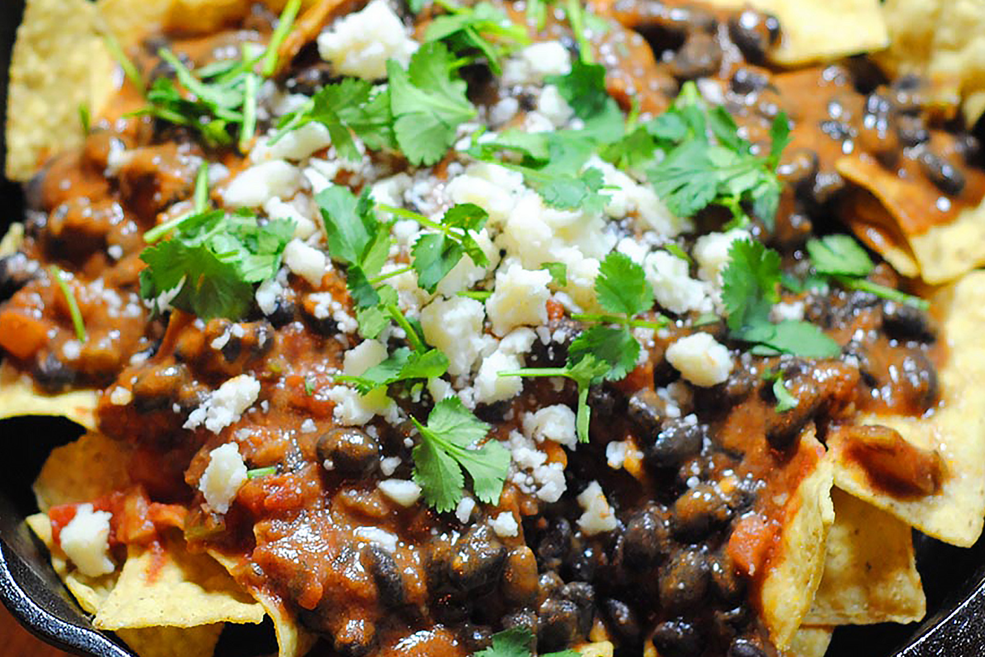 Close-up of black bean chilaquiles garnished with white cheese and cilantro