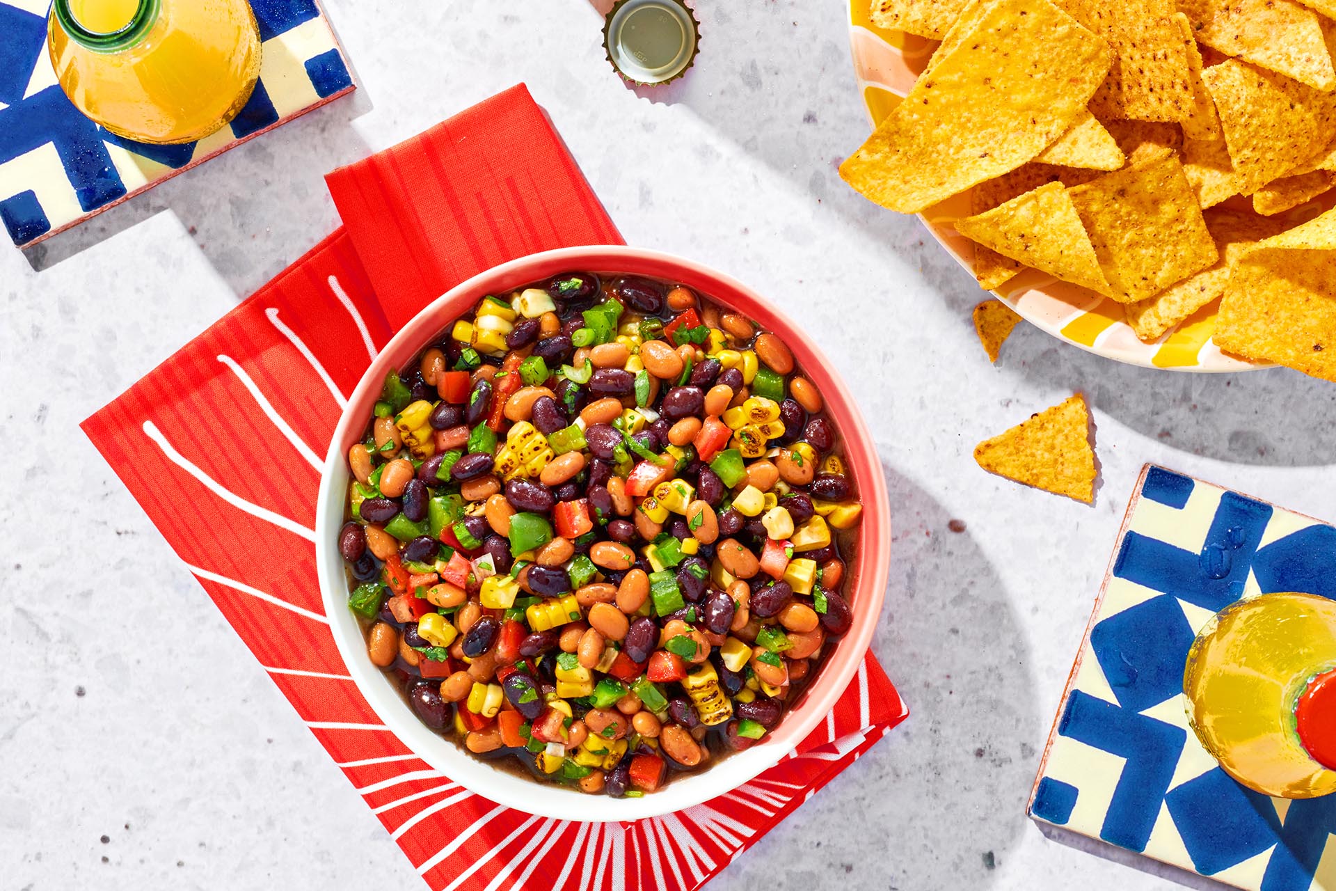 A bowl of grilled corn salsa with a bowl of chips.
