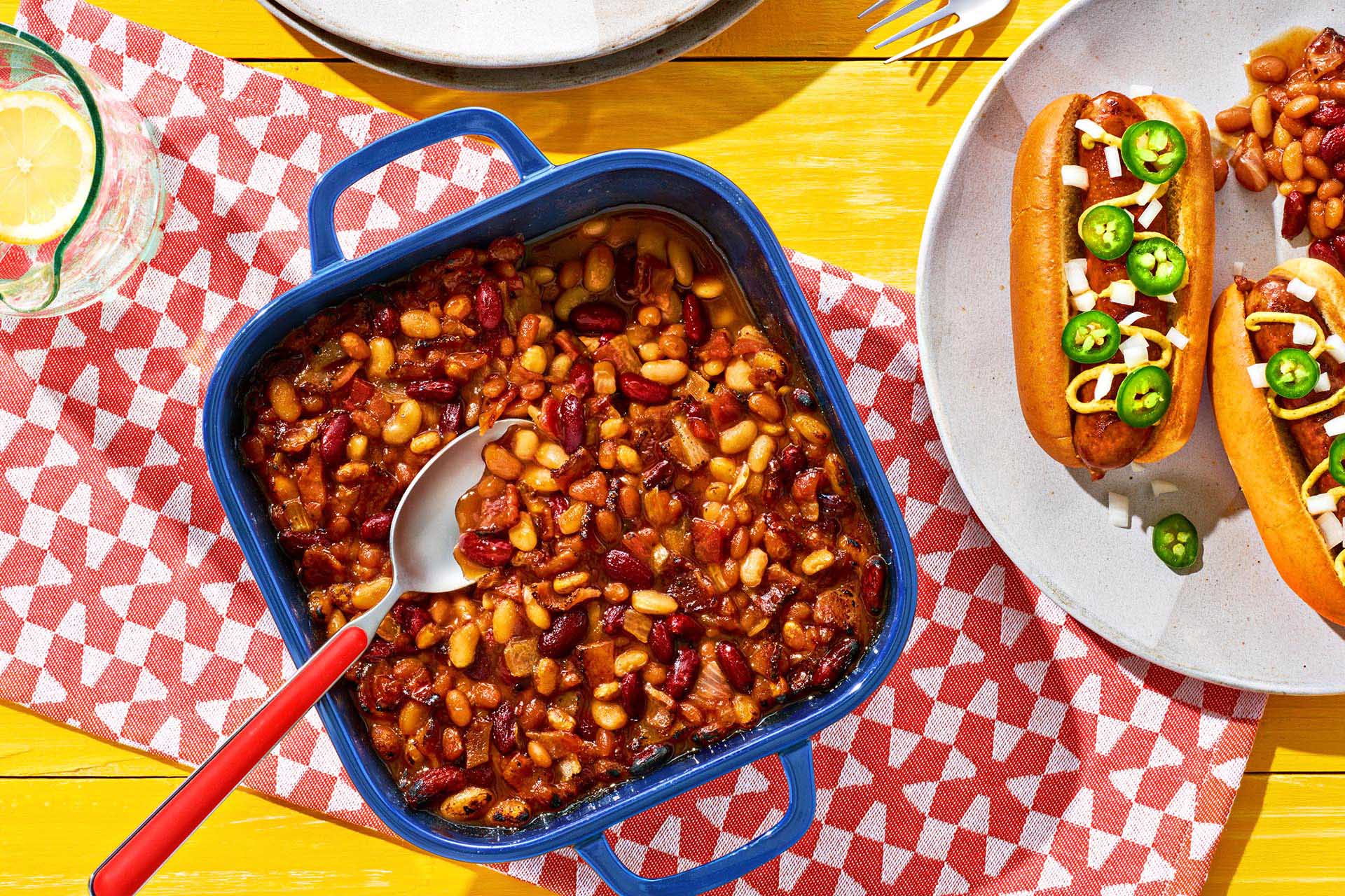 Baked Beans Casserole in a blue enamel dish atop a colorful napkin.