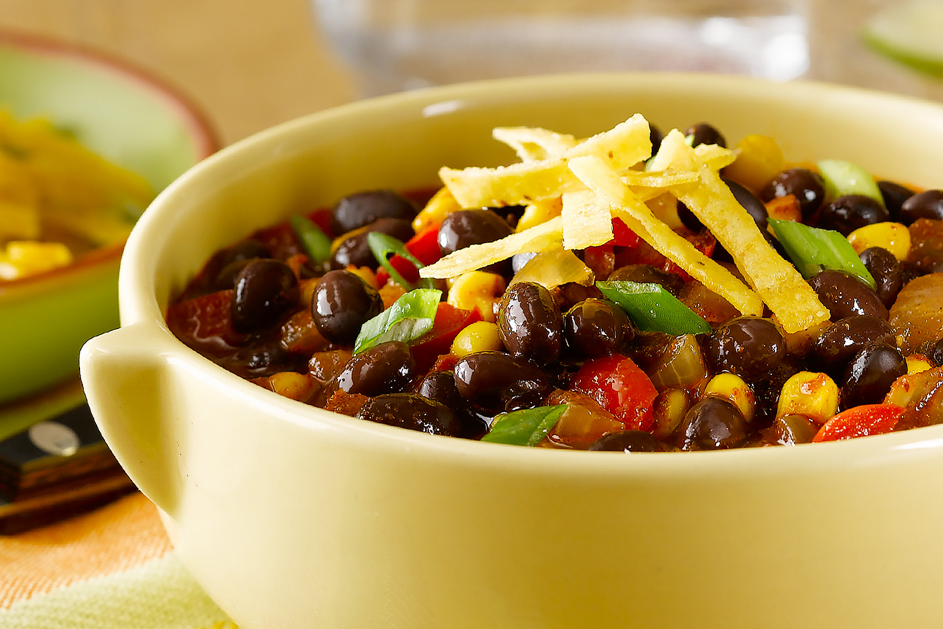 Black bean chili topped with tortilla strips in a pale green bowl