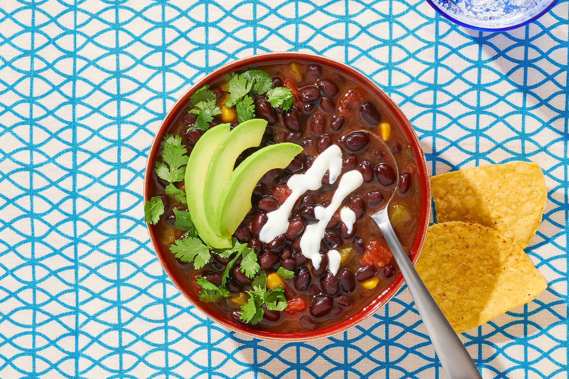 Bowl of black bean soup garnished with cilantro, sour cream and avocado