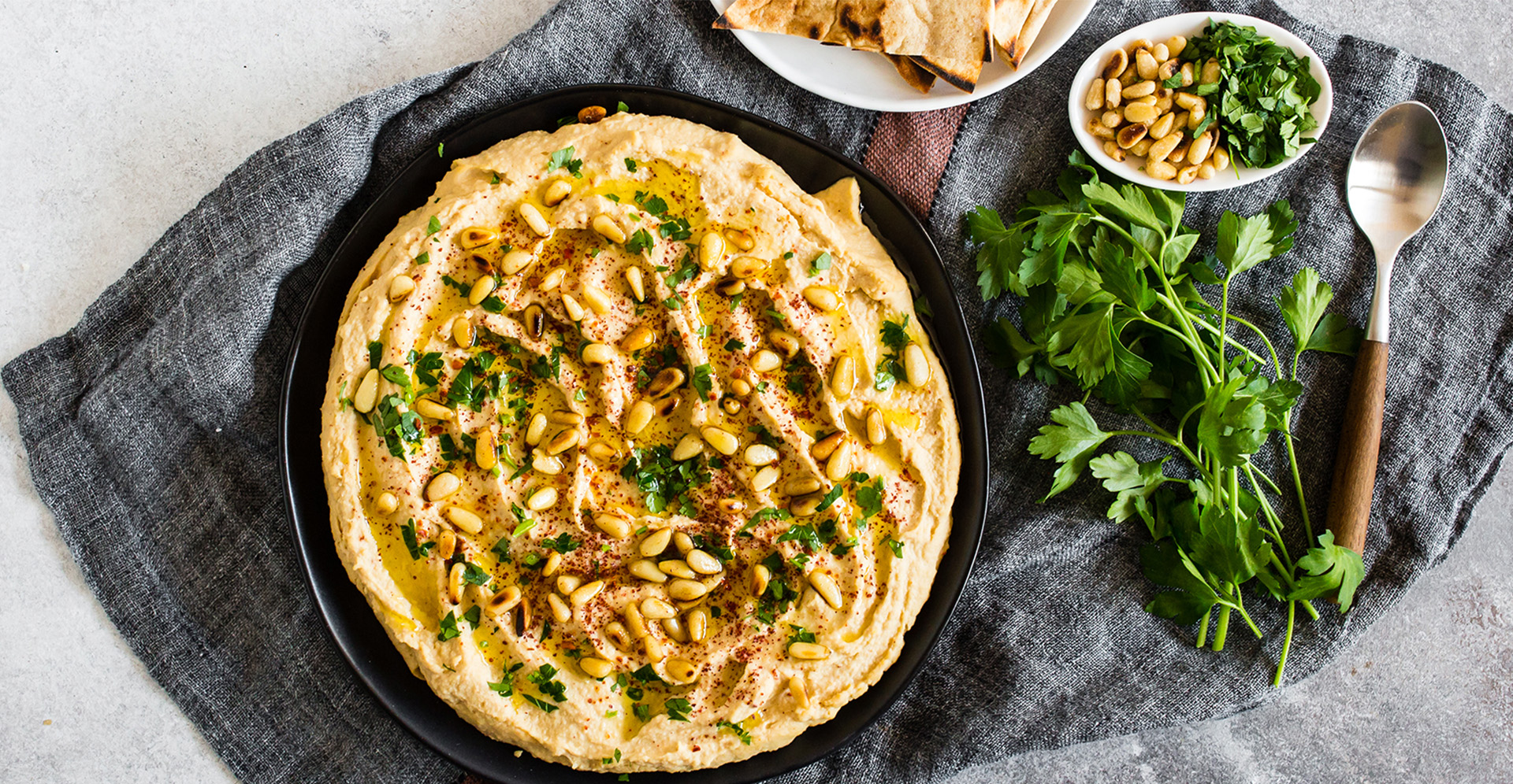 Hummus with pinenuts on top in a black bowl