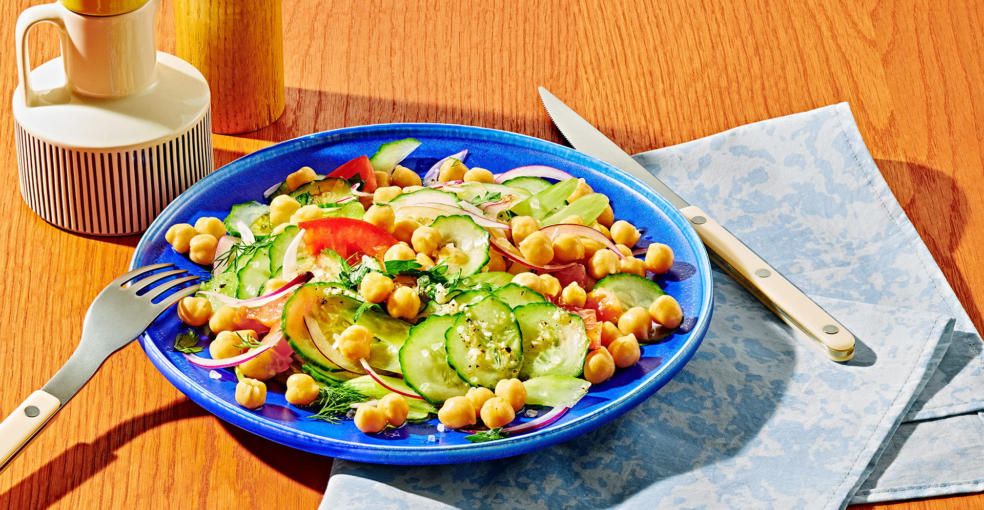 Salad with pickles, garbanzo beans, red onion and herbs in a blue bowl