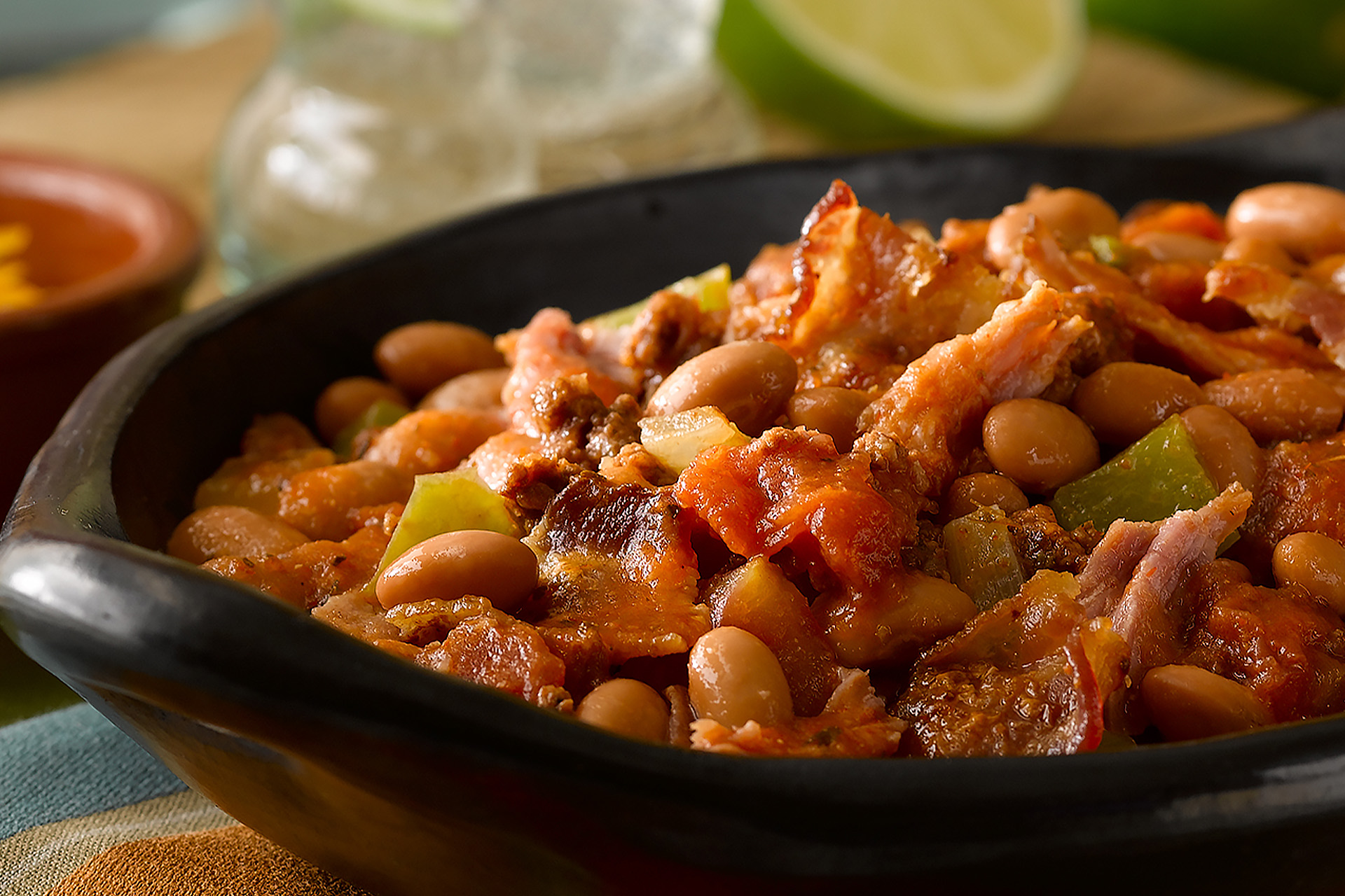 Pulled pork and pinto beans with chorizo, peppers and bacon in black baking dish