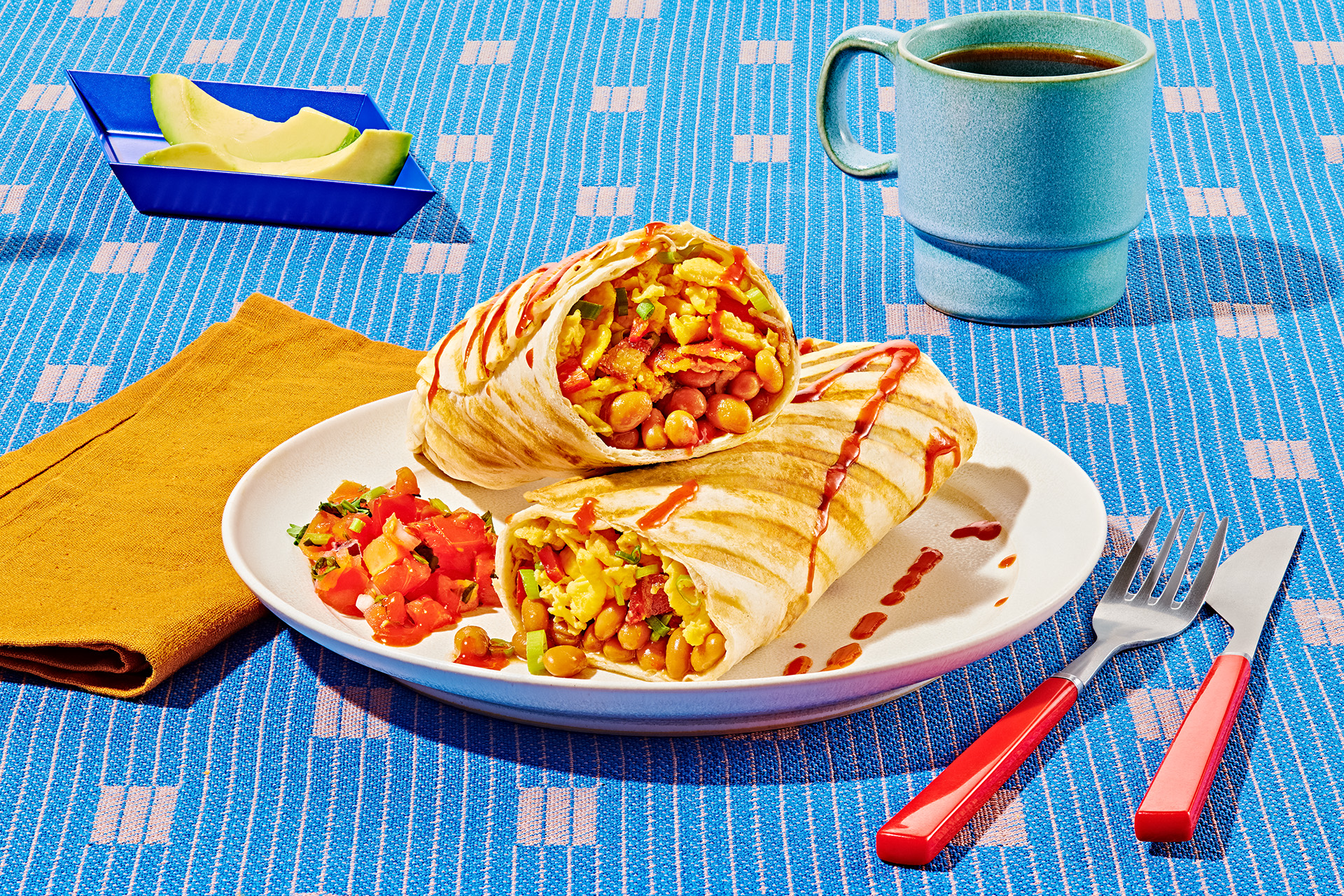 Grilled egg and baked bean breakfast burritos with bacon and tomato salsa on a white plate on a blue tablecoth