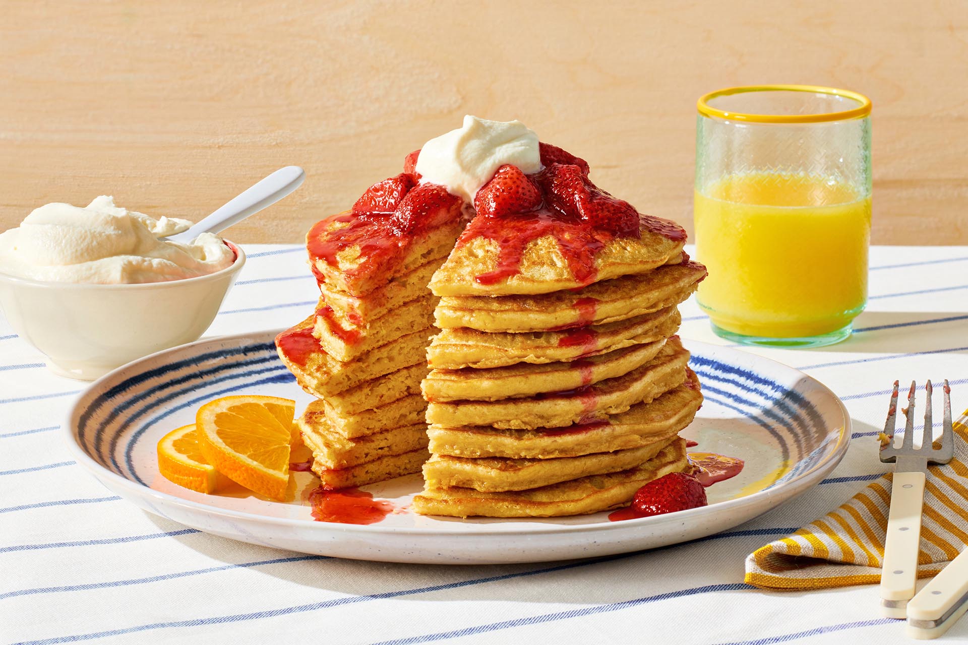 A tall stack of chickpea pancakes topped with strawberries and whipped cream