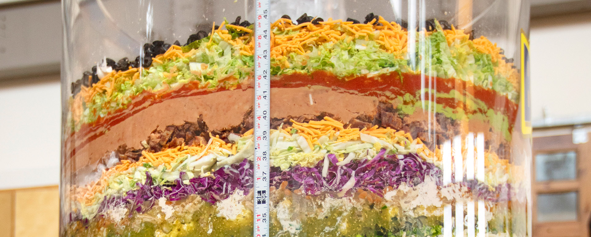 A close-up of 70-layer bean dip in a clear cylinder