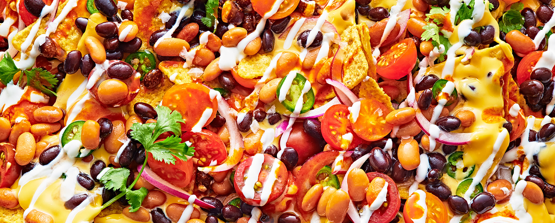 A close-up of nachos with black beans, cheese, jalapenos and sour cream