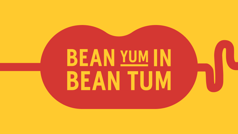 Playful text on a yellow background reading 'BEAN YUM IN BEAN TUM' in red and yellow, shaped like a winding bean.