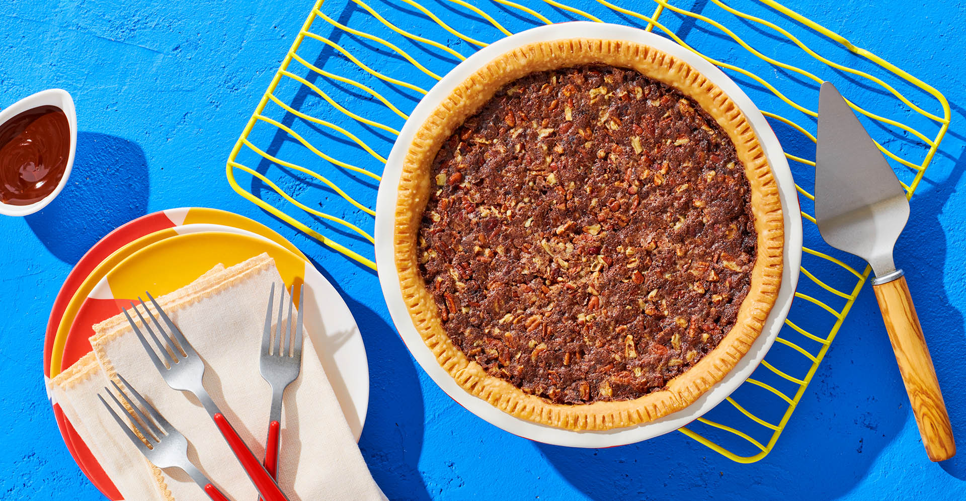 Whole pinto bean pecan pie on a white plate and cooling rack.