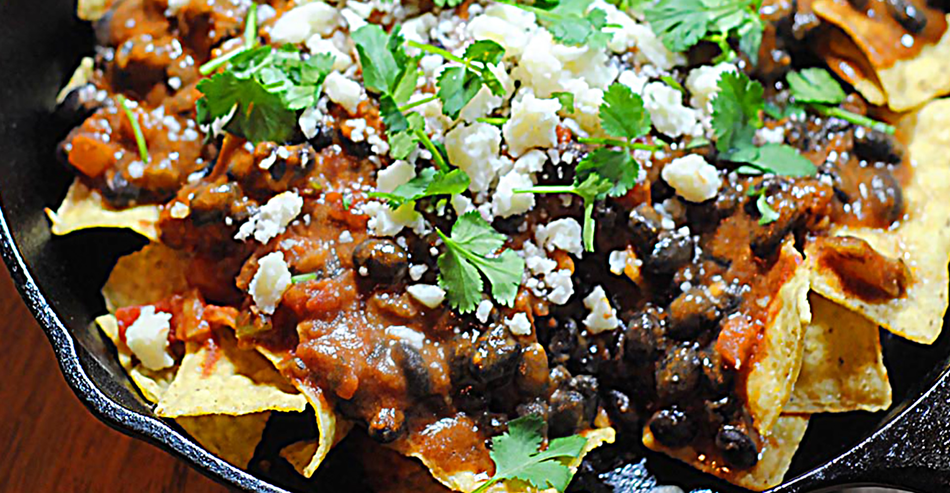 Close-up of black bean chilaquiles garnished with white cheese and cilantro