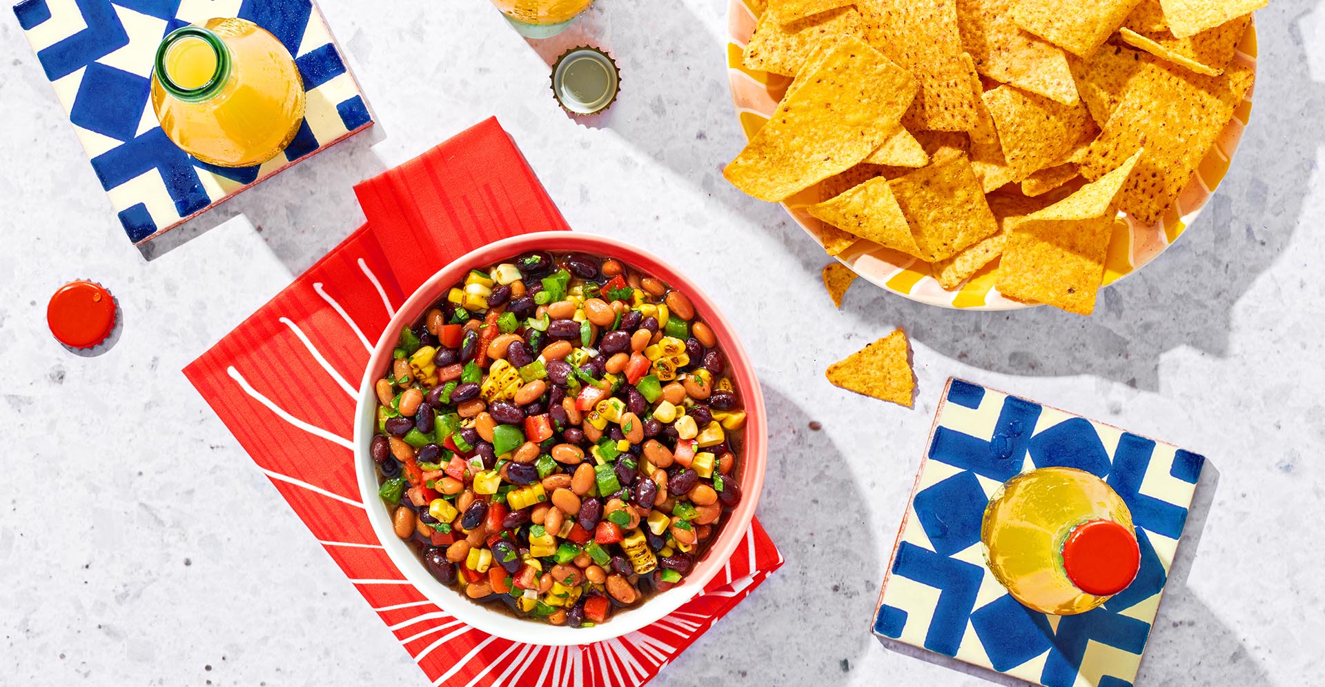 A bowl of grilled corn salsa with a bowl of chips.