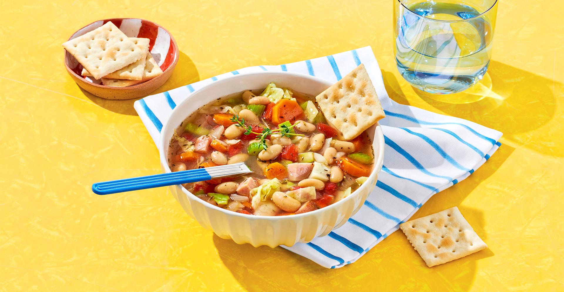 A bowl of white bean and ham soup served with saltine crackers