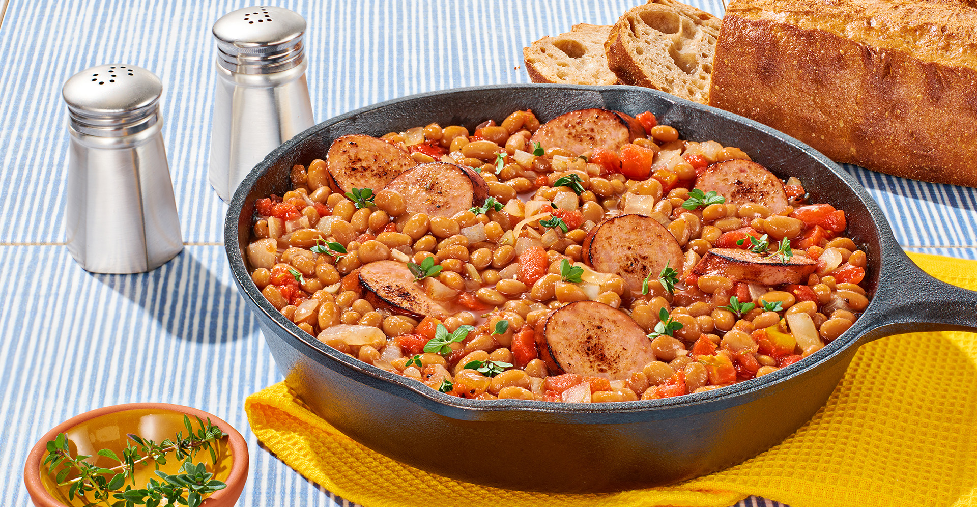 Baked bean and sliced sausage casserole in a cast iron skillet