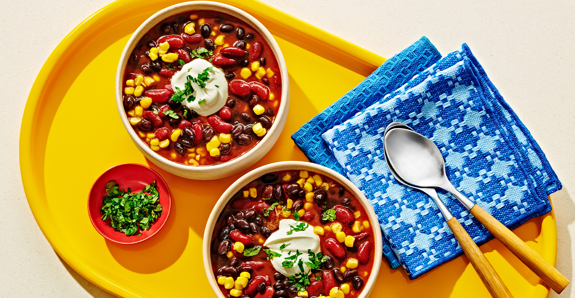 Bowl of chili with black beans, kidney beans, and corn topped with sour cream