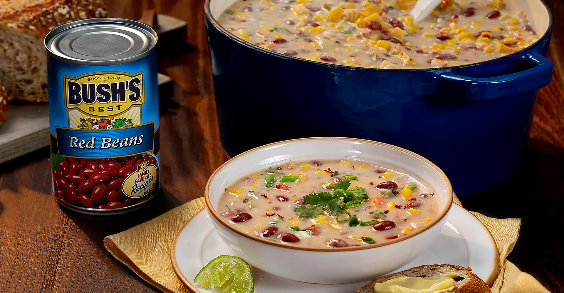 Tomato and cococut corn chowder with plantains in a white bowl with a can of Bush's Best Red Beans