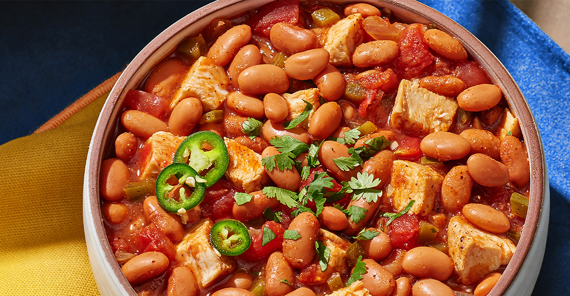 Pinto bean and chicken chili in bowl with japalenos and chilantro