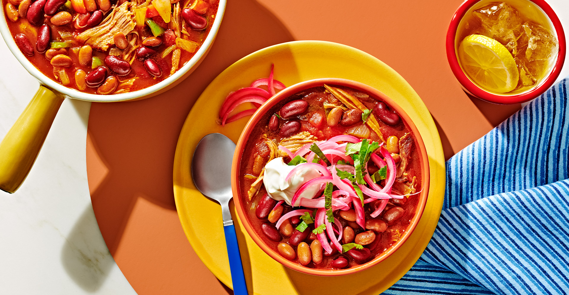 Chicken and bean chili in yellow bowl garnished with sour cream and onion