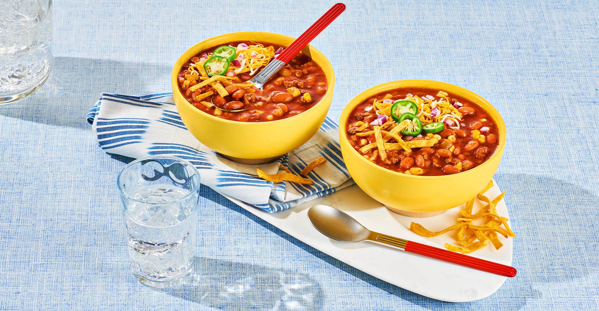 Two yellow bowls filled with Slow Cooker Taco Soup with fresh jalapeño, cheese and coupon toppings.