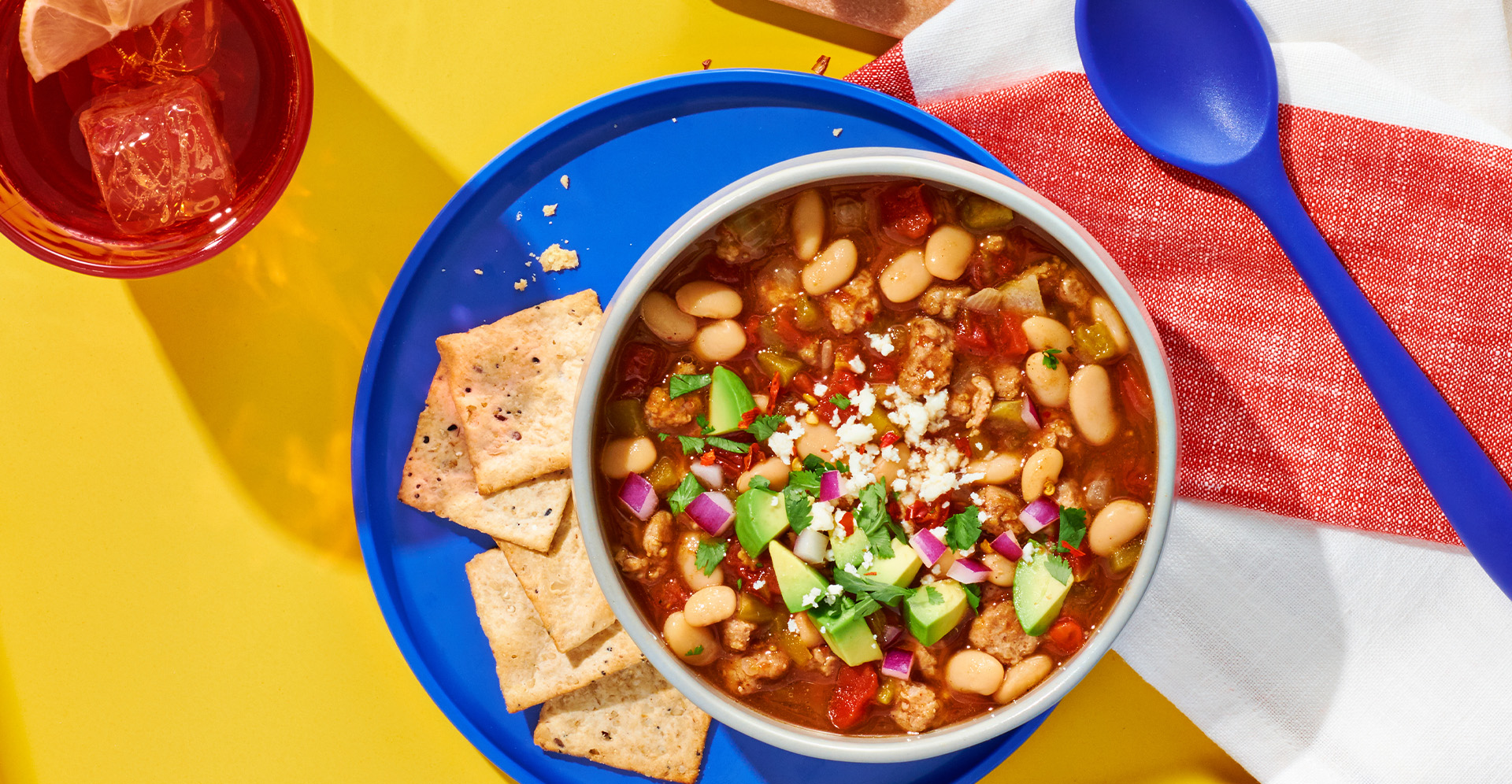 White bean and ground turkey chili in a bowl, on a blue plate with crackers