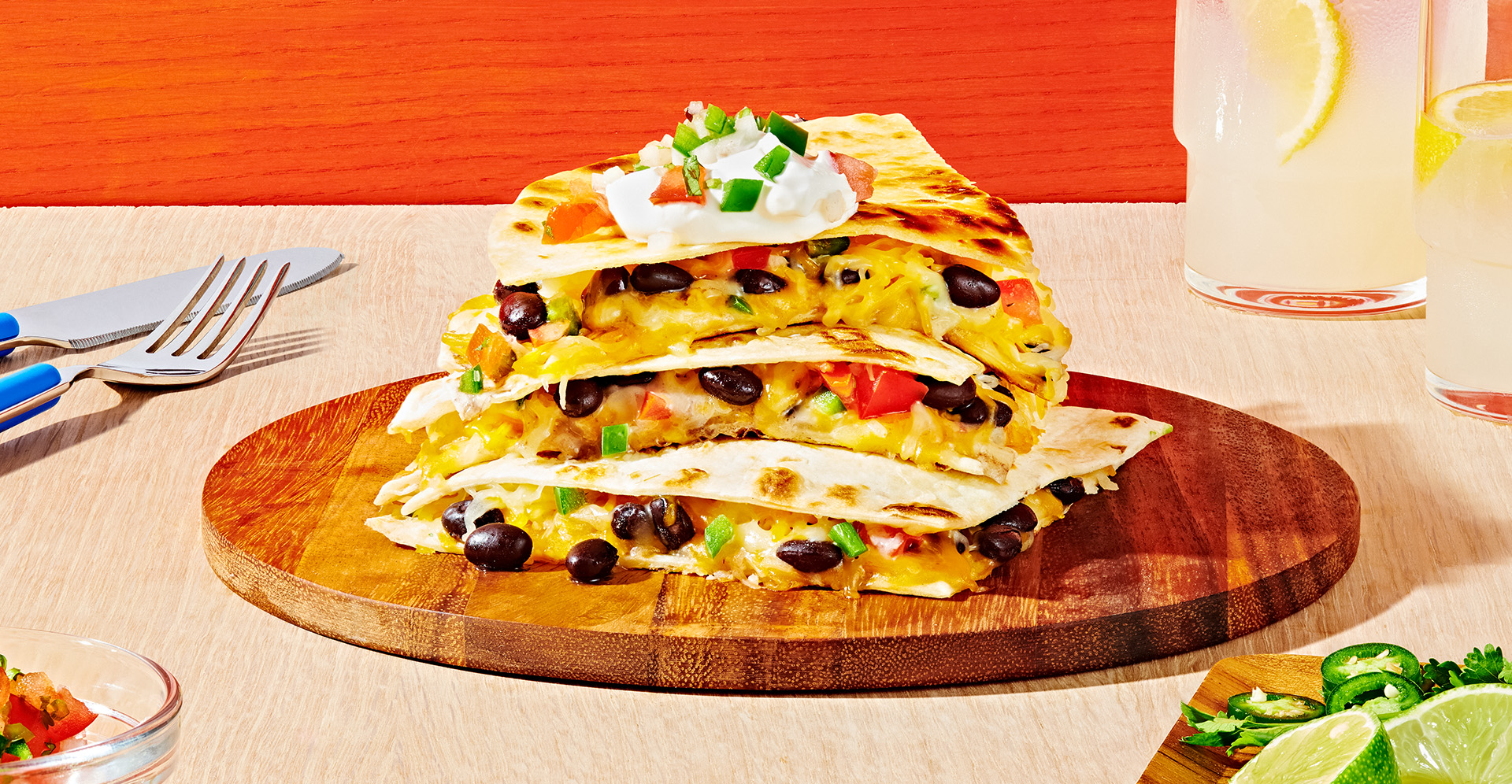Three pieces of black bean quesadillas stacked on top of each other on a wooden plate