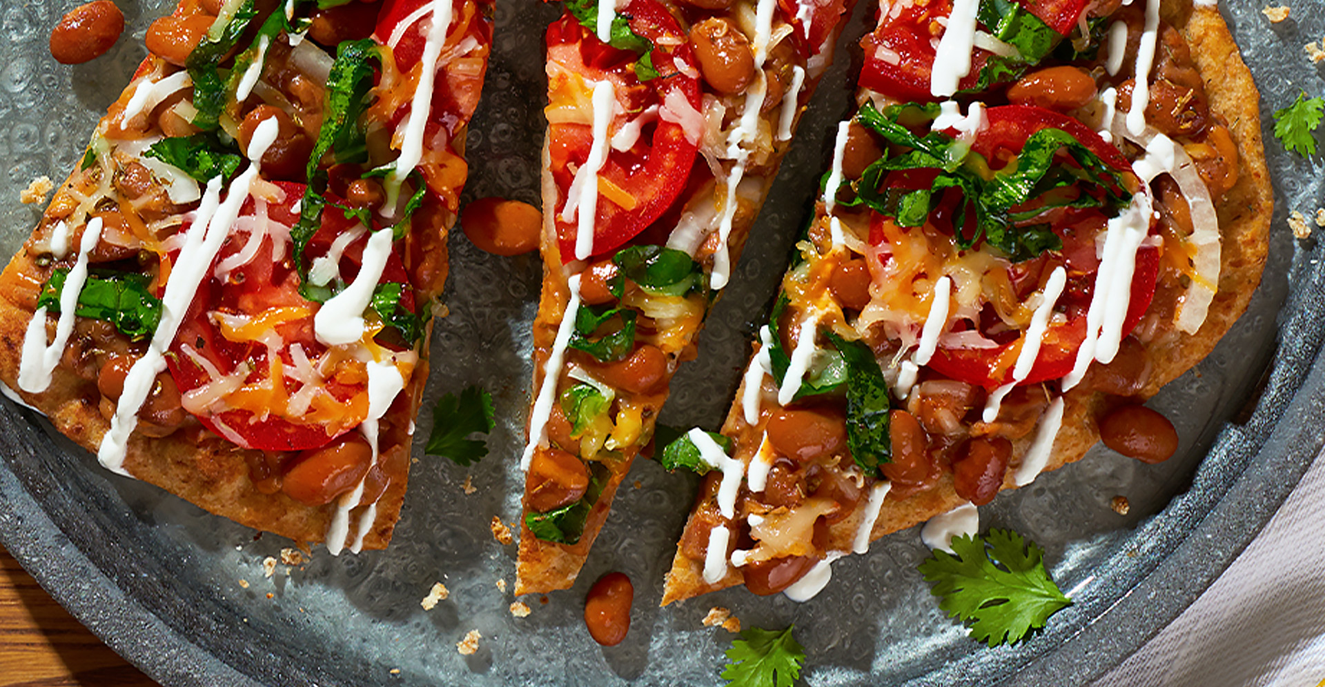 Slices of flatbread with beans, tomatos and spinach