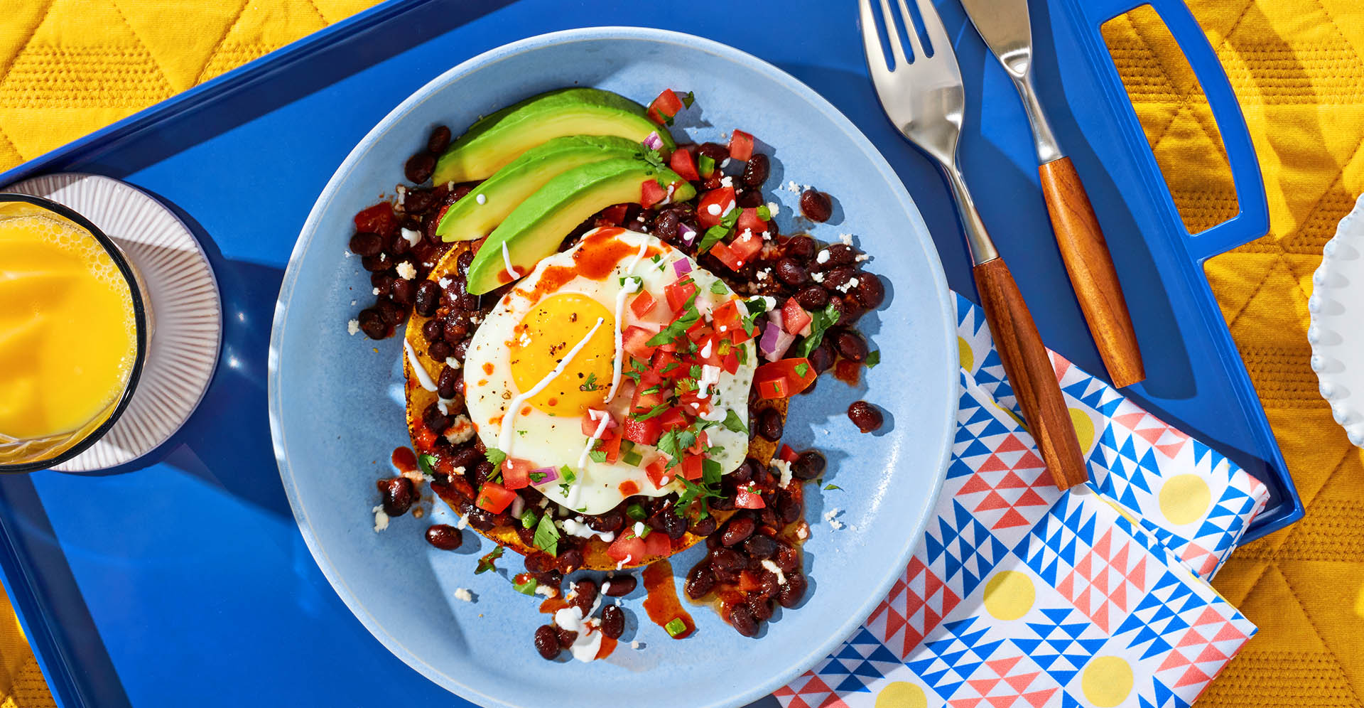 Huevos rancheros with a fried egg on top of Bush's Beans, tomato salsa and a side of avocado slices.