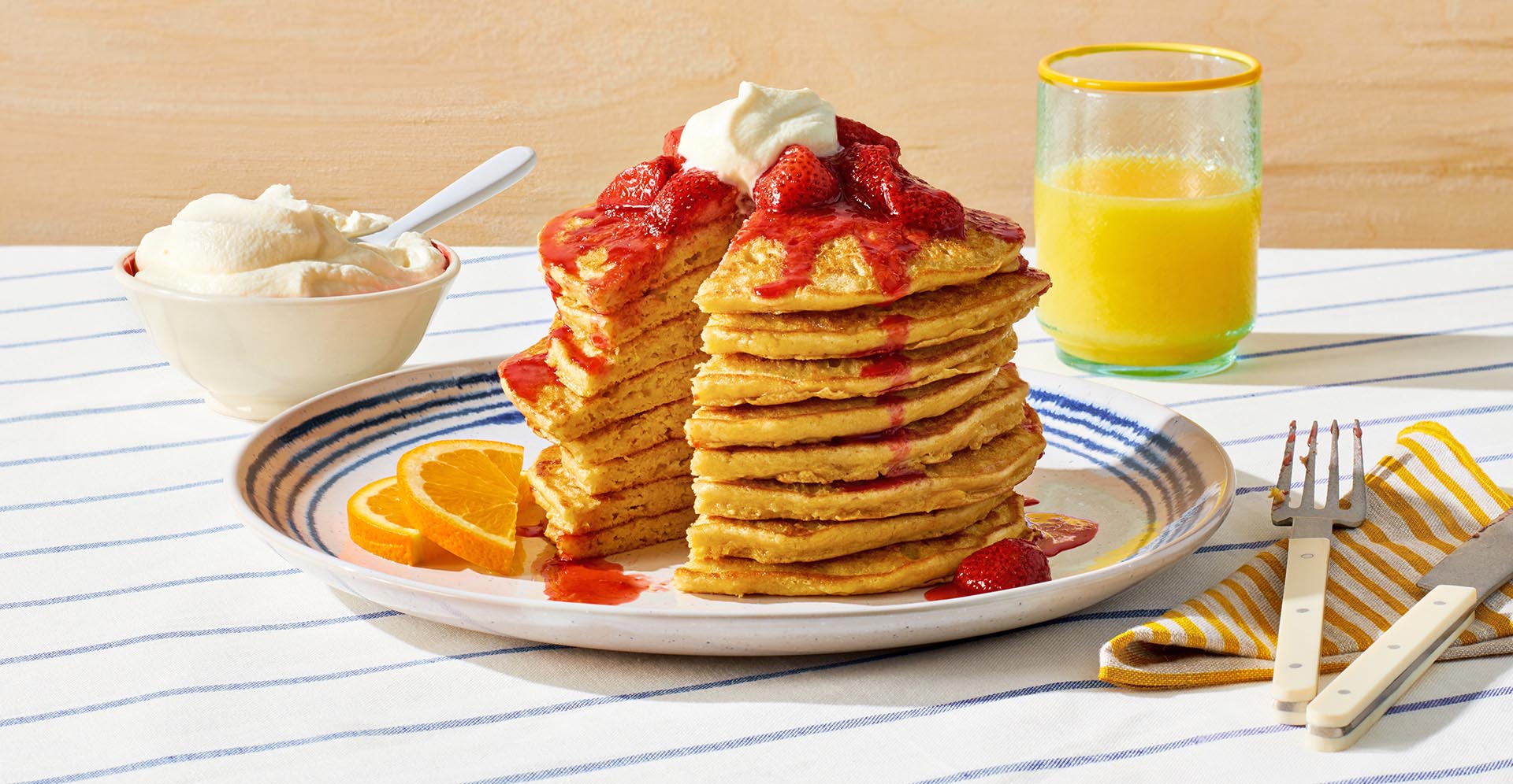 A tall stack of chickpea pancakes topped with strawberries and whipped cream