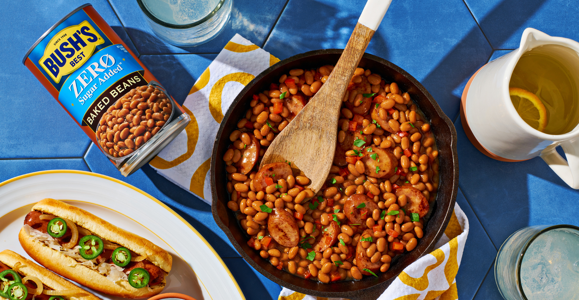 Chicken apple sausage baked beans in a cast iron skillet next to a can of Bush's Zero Sugar Added Baked beans. 