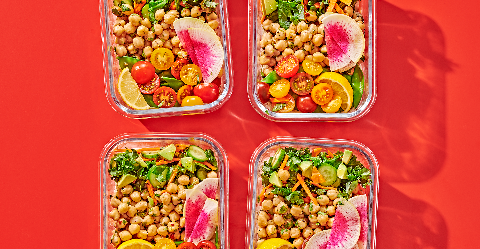 four lunch containers filled with colorful salads