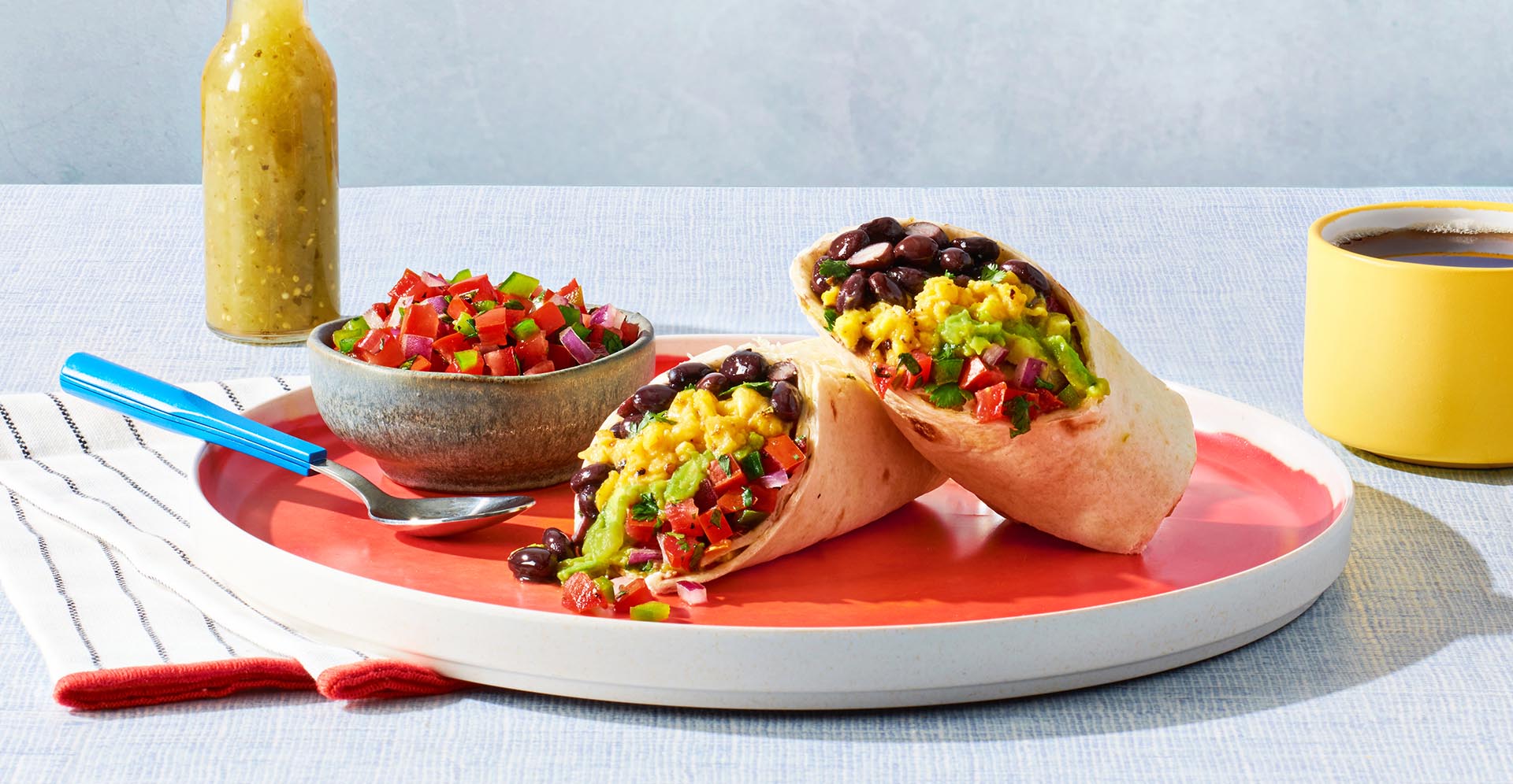 Sliced bean, avocado and egg burrito on a plate with a cup of coffee
