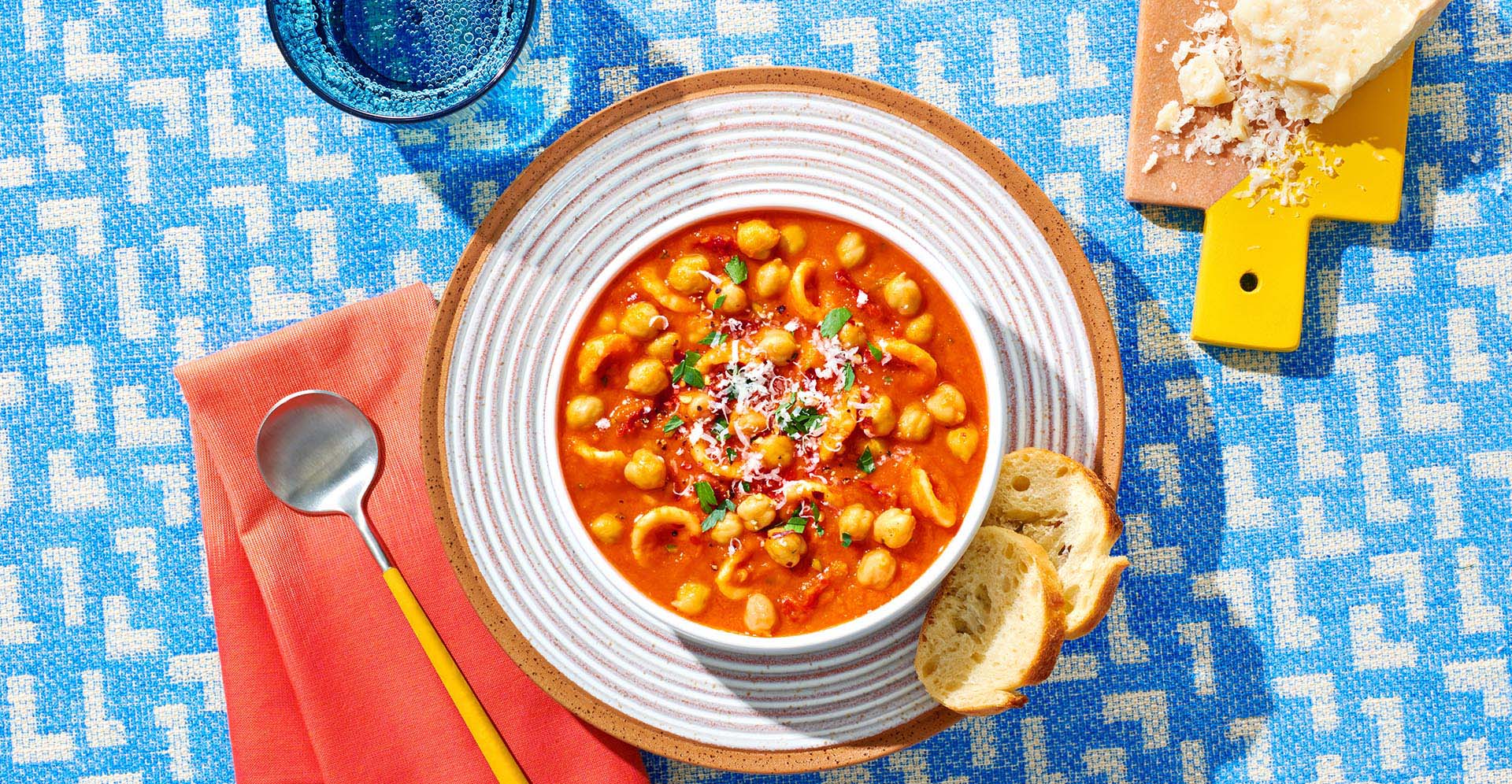 A bowl of Tuscan garbanzo bean and sun dried tomato soup with toast rounds on a plate